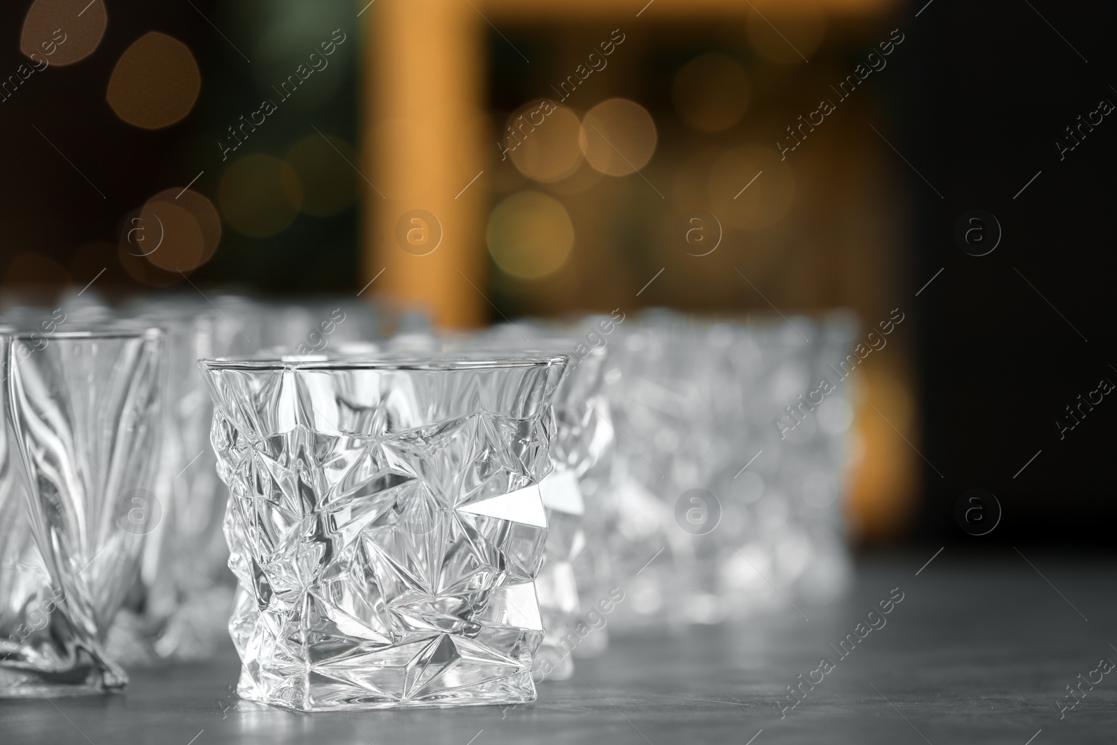 Photo of Empty glasses on table against blurred background. Space for text
