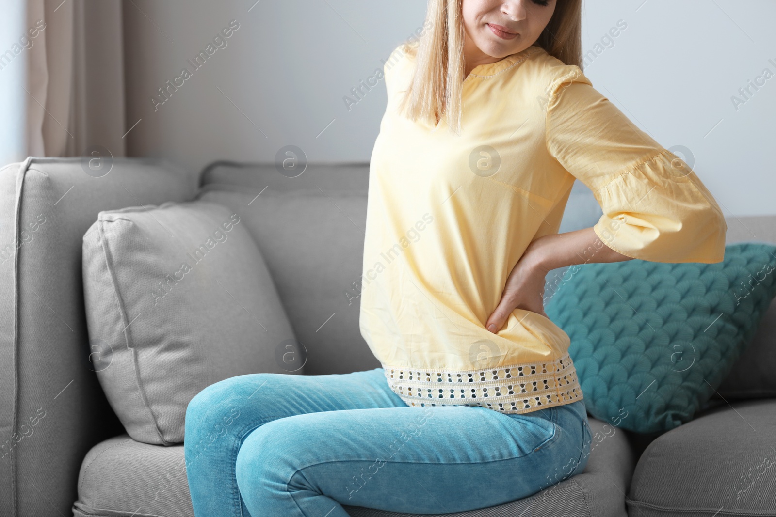 Photo of Young woman suffering from back pain at home