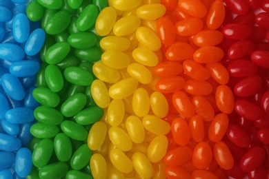 Photo of Tasty bright jelly beans as background, top view