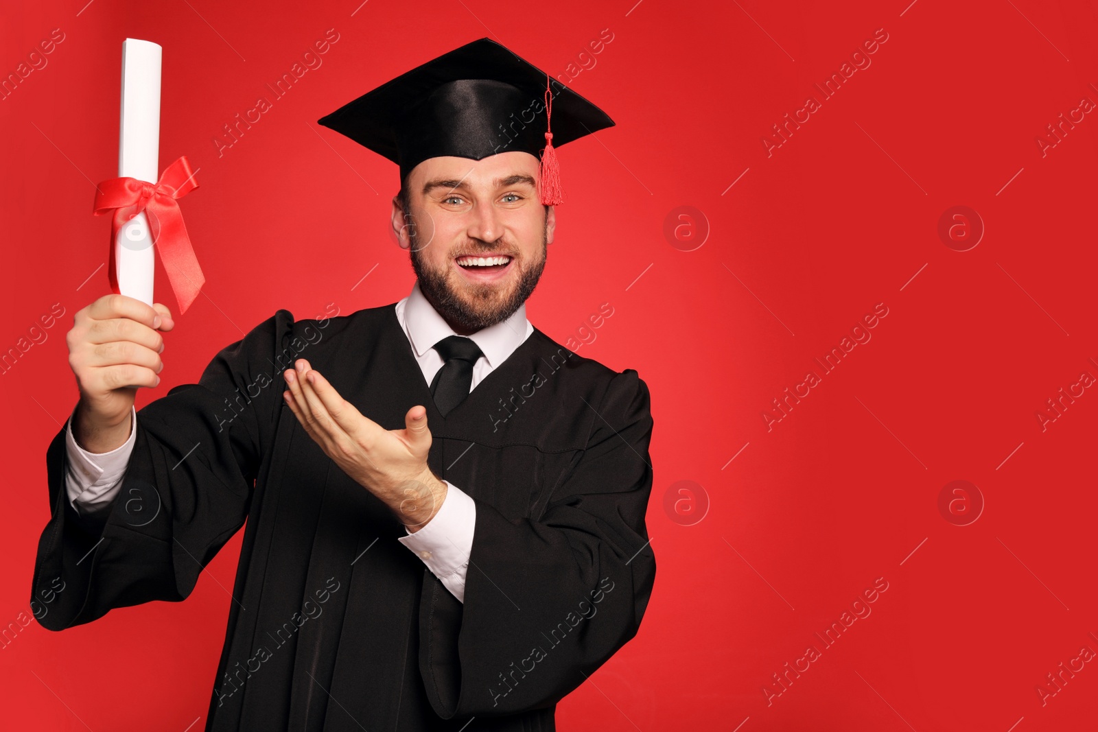 Photo of Happy student with graduation hat and diploma on red background. Space for text