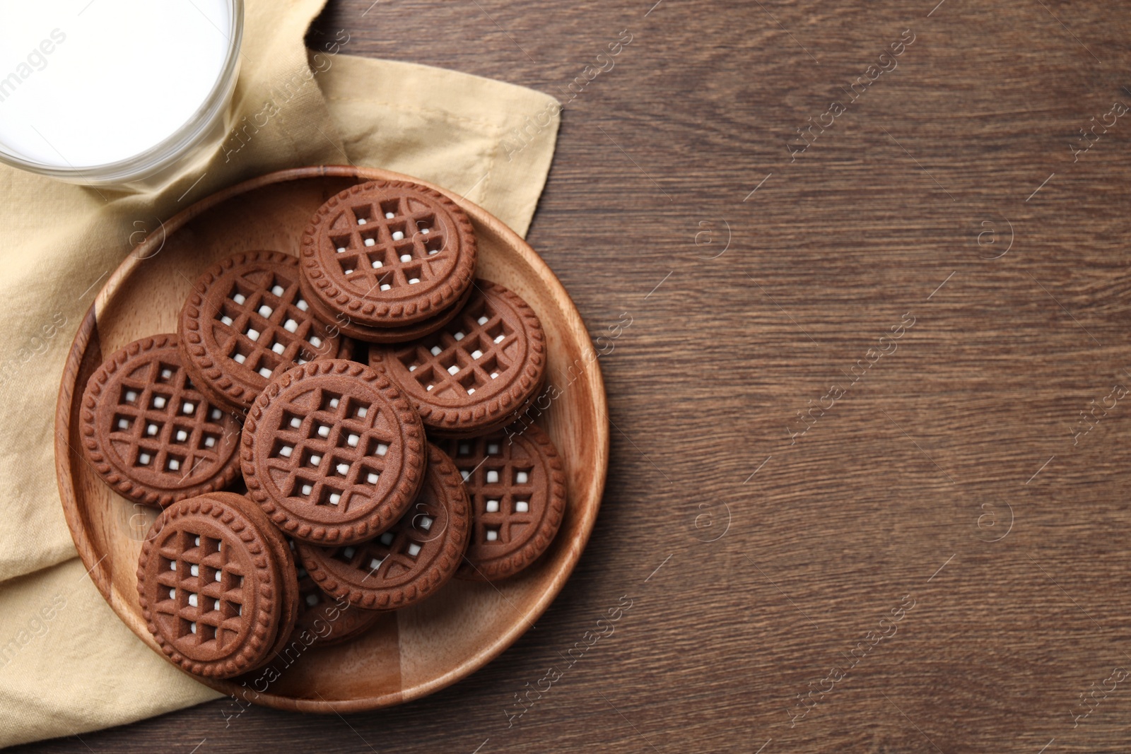 Photo of Tasty chocolate sandwich cookies with cream on wooden table, top view. Space for text