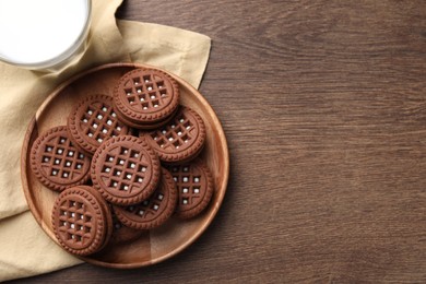 Tasty chocolate sandwich cookies with cream on wooden table, top view. Space for text