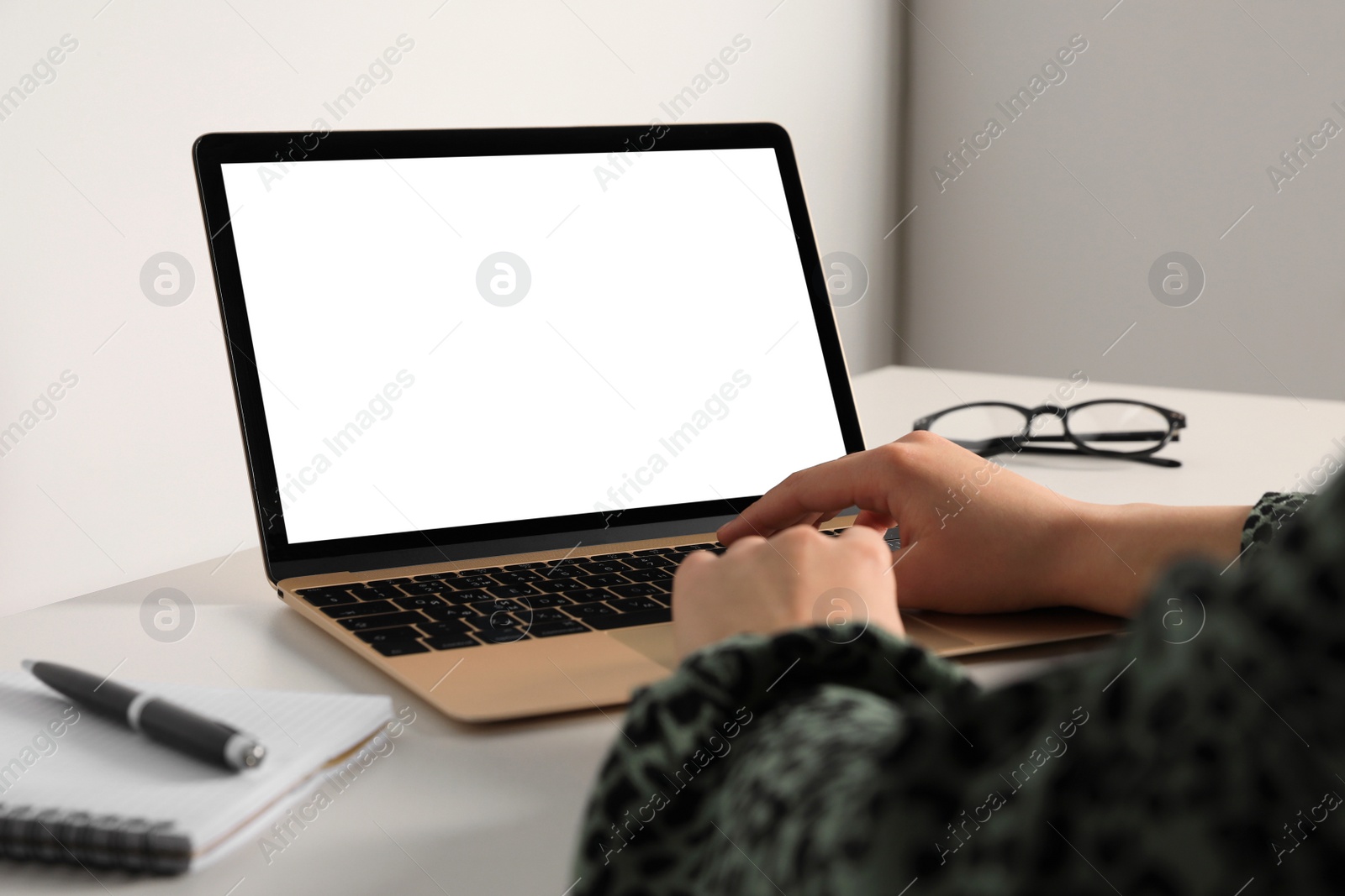 Photo of Woman working on modern laptop at table in office, closeup. Mockup for design