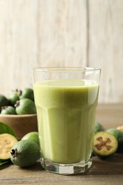 Photo of Fresh feijoa smoothie and fresh fruits on wooden table, closeup