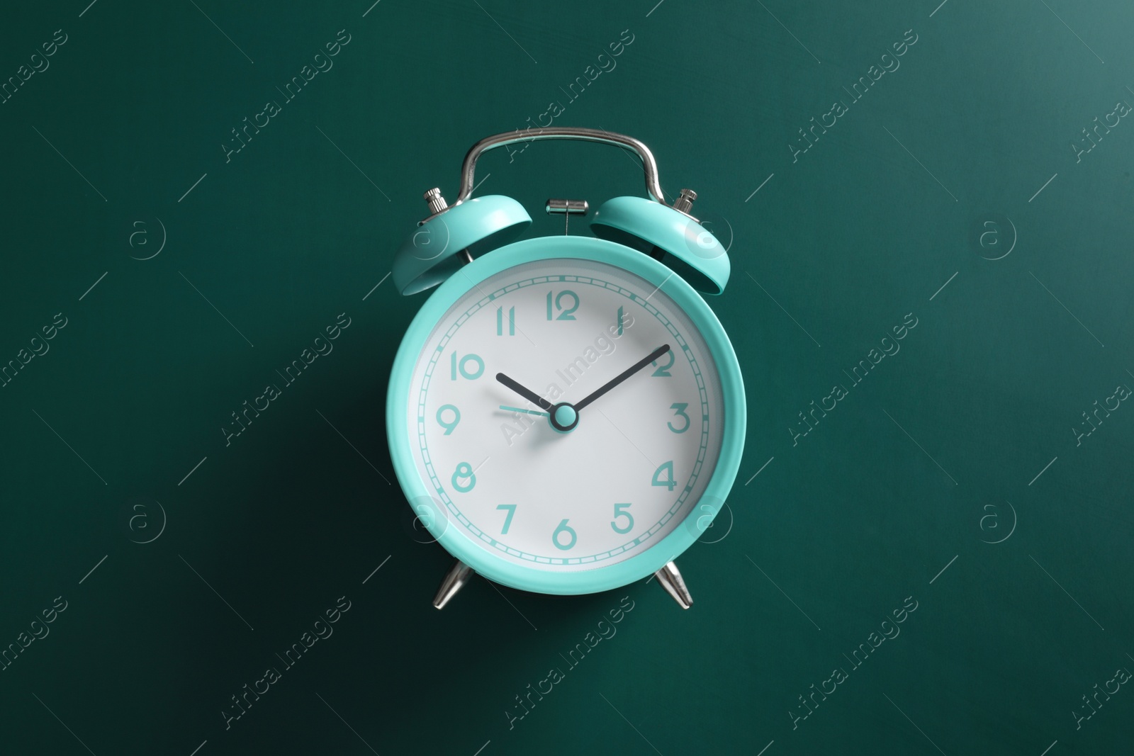 Photo of Alarm clock on green background, top view. School time