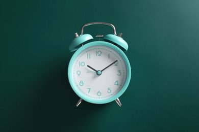 Alarm clock on green background, top view. School time