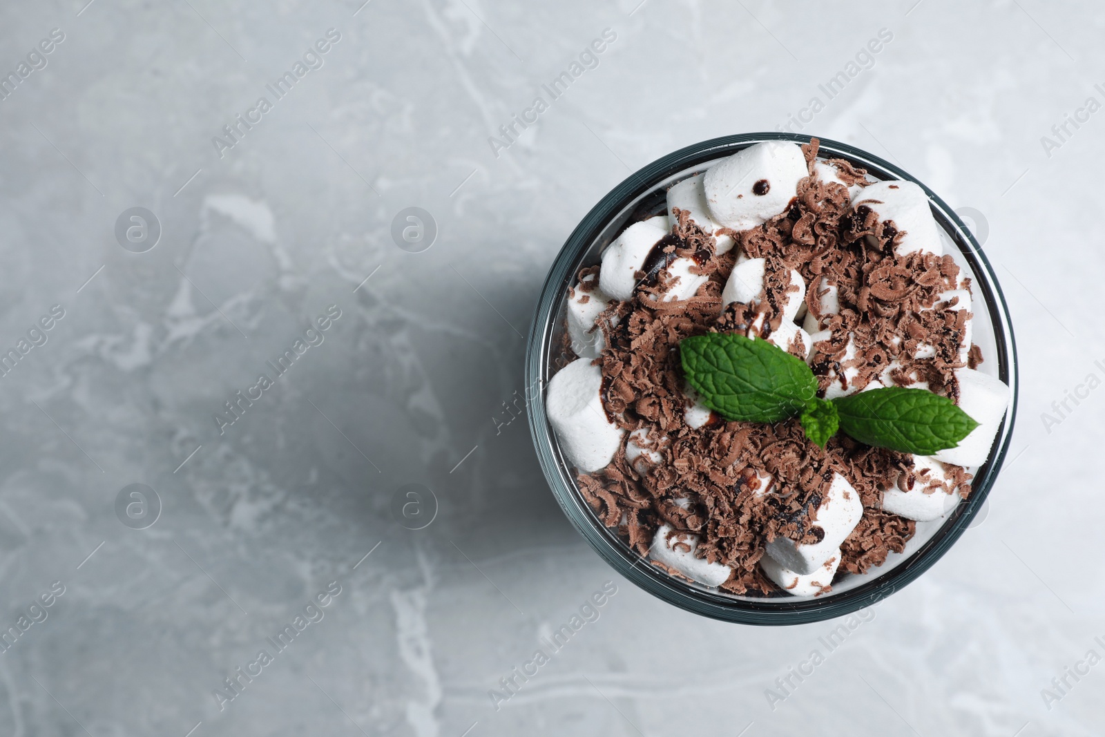 Photo of Glass of delicious hot chocolate with marshmallows and fresh mint on light grey marble table, top view. Space for text