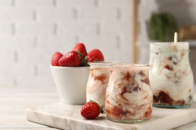 Photo of Tasty yoghurt with jam and strawberries on white wooden table, closeup