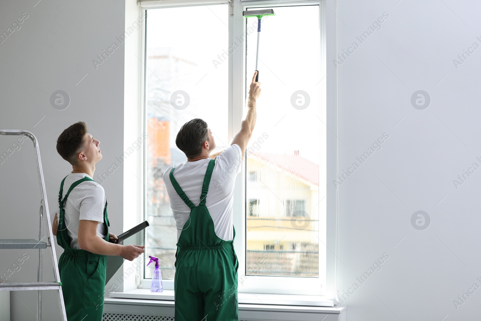 Photo of Professional workers tinting window with foil indoors. Space for text