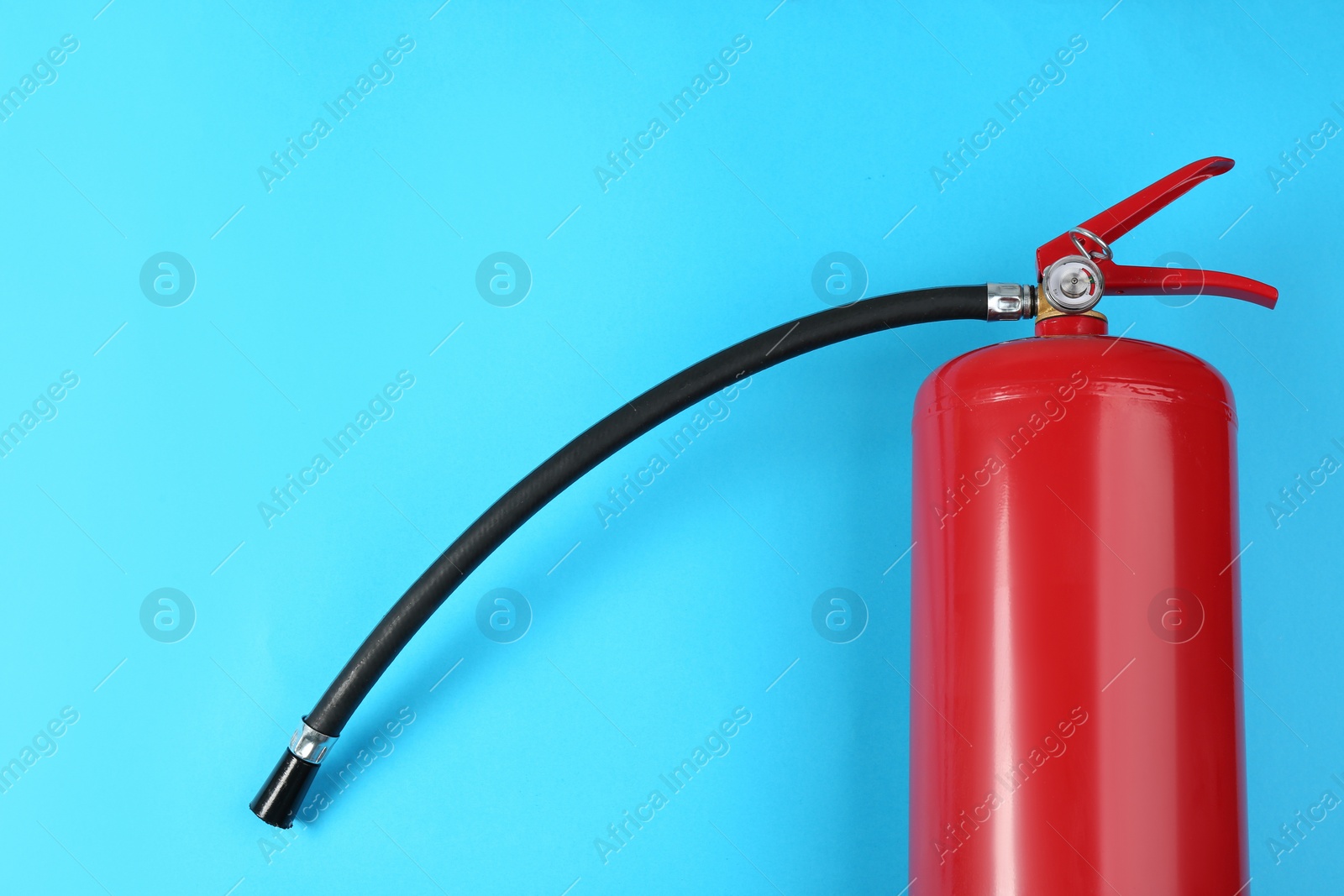 Photo of Fire extinguisher on light blue background, top view