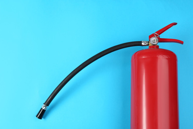 Fire extinguisher on light blue background, top view