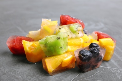 Photo of Fruit and berry ice cubes on grey background