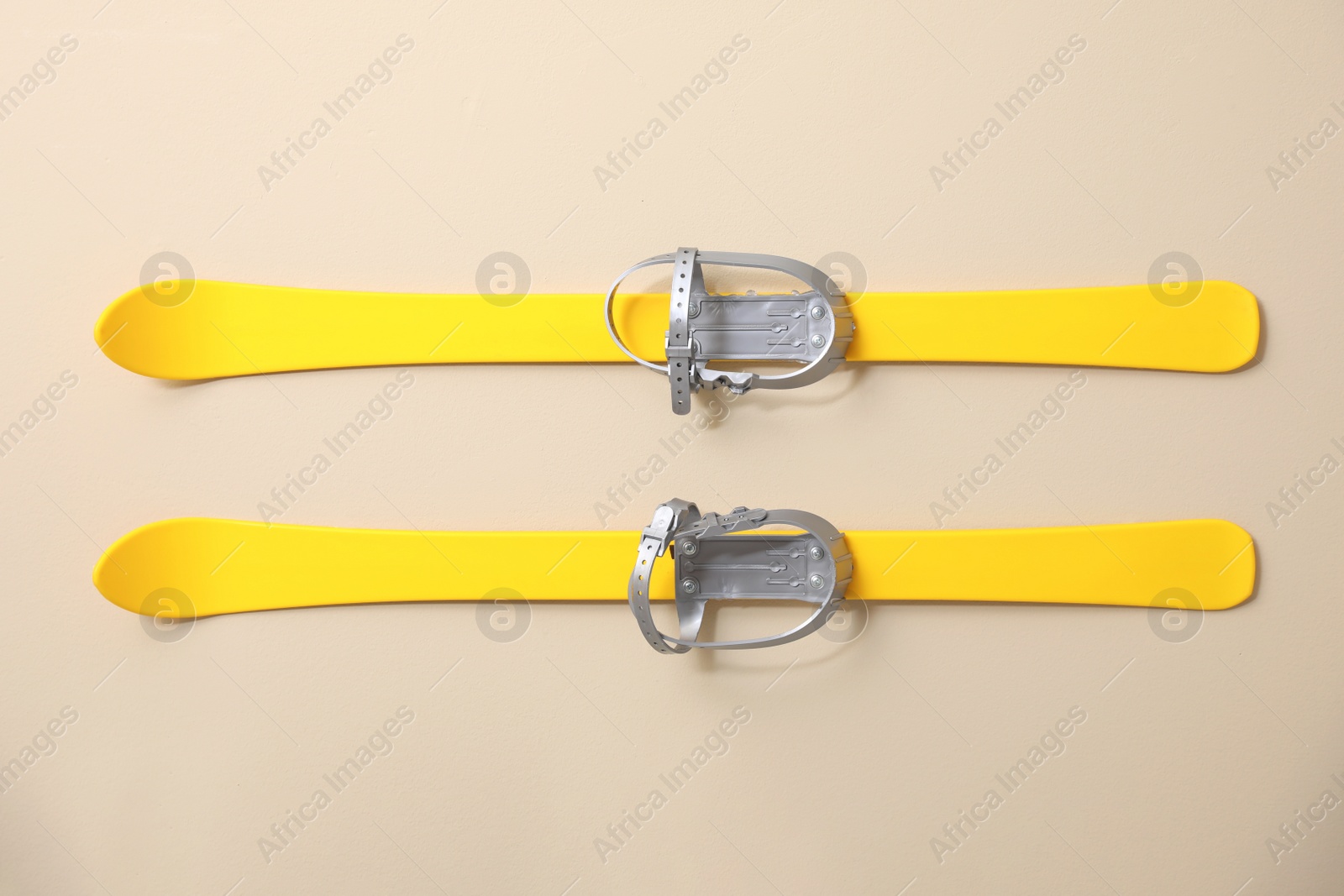 Photo of Yellow skis on beige background, flat lay. Sports equipment