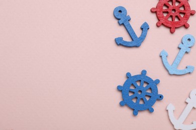 Anchor and ship wheel figures on pale pink background, flat lay. Space for text
