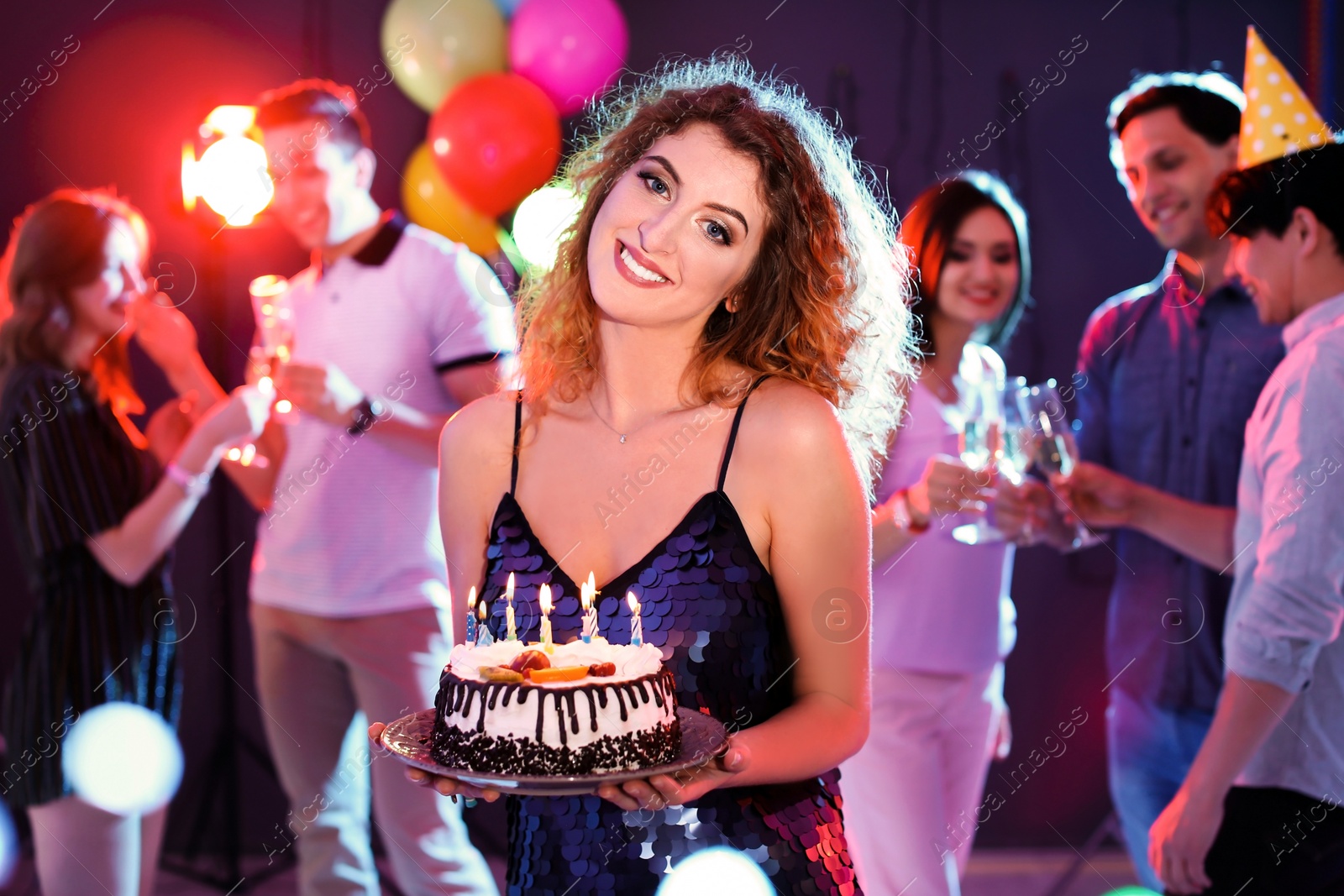 Photo of Young woman with birthday cake at party in nightclub