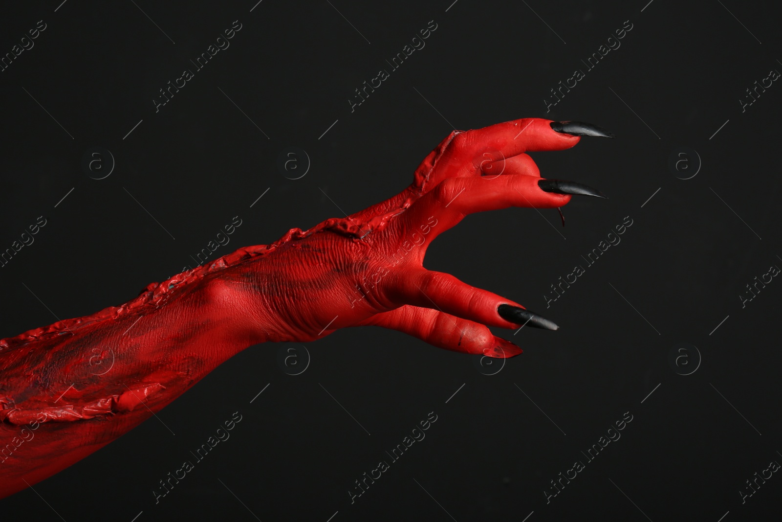 Photo of Scary monster on black background, closeup of hand. Halloween character