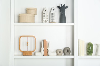 White shelves with books and different decor indoors. Interior design