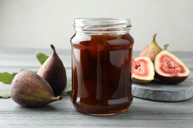 Jar of tasty sweet jam and fresh figs on grey table