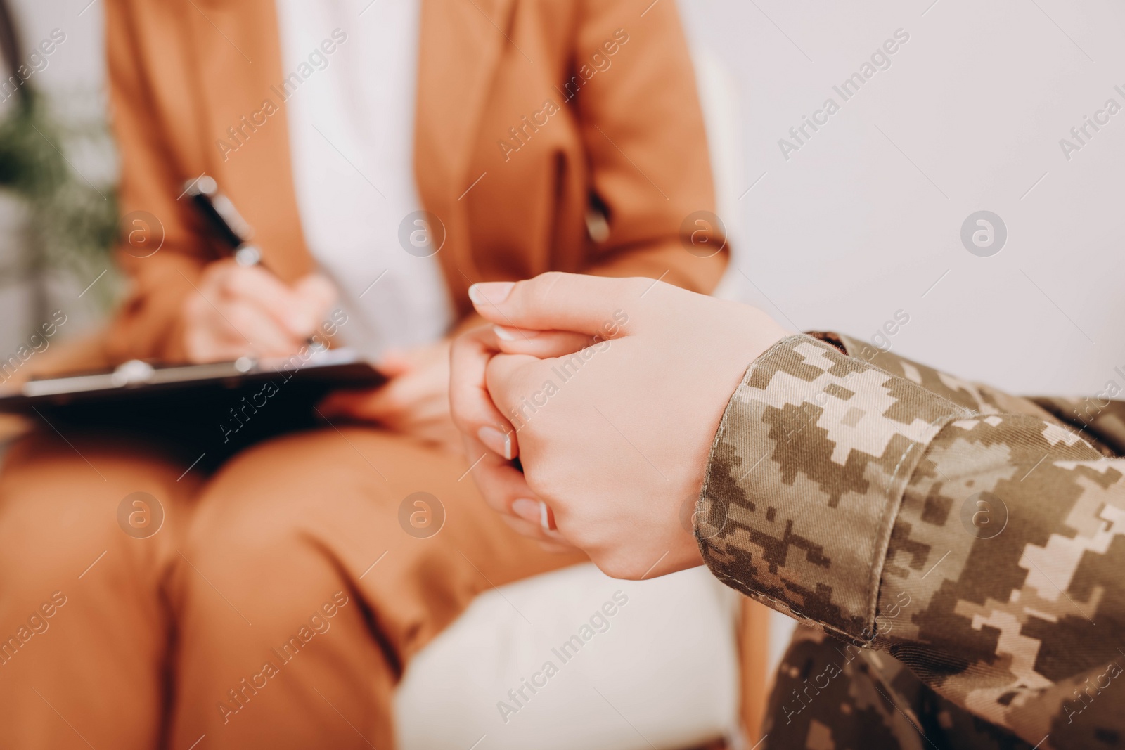 Photo of Female military officer sitting with psychologist in office, focus on hands