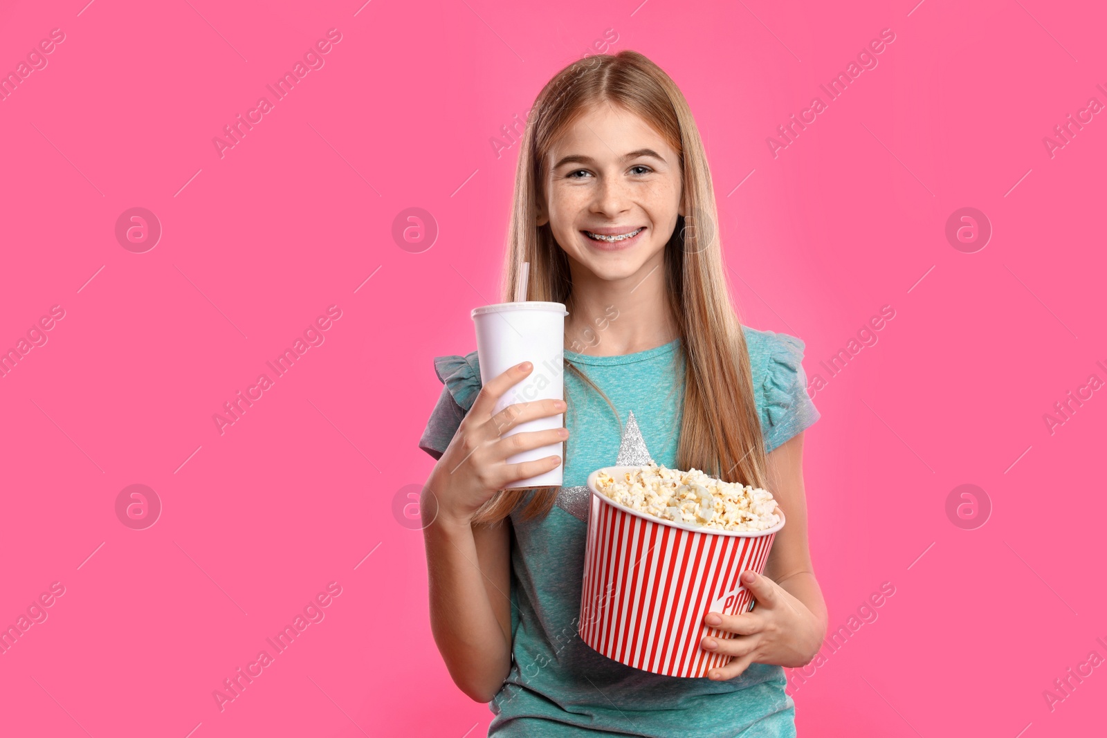 Photo of Teenage girl with popcorn and beverage during cinema show on color background