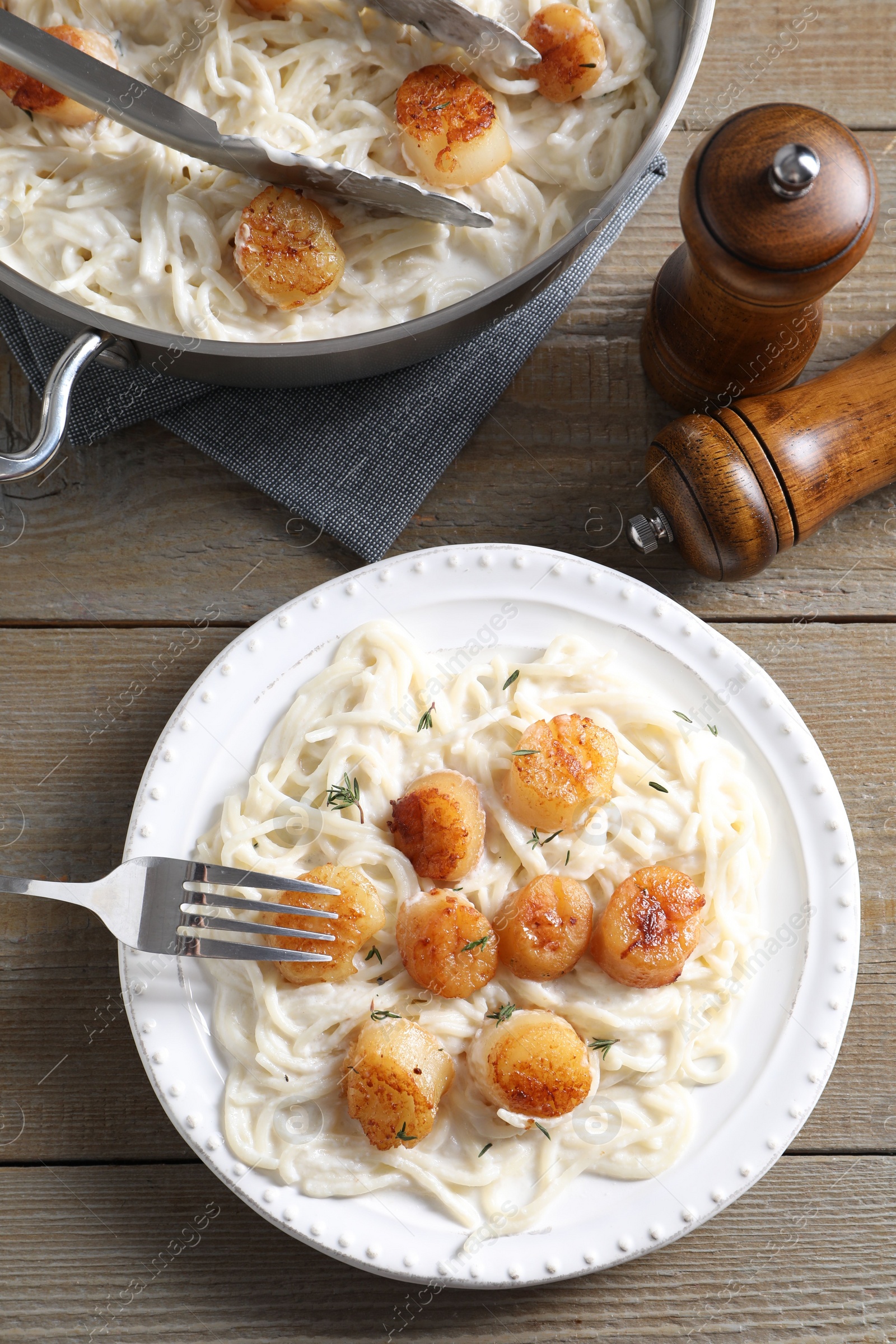 Photo of Delicious scallop pasta served on wooden table, flat lay