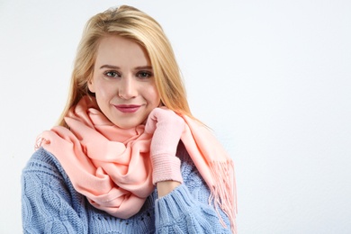 Image of Pretty young woman wearing warm sweater, scarf and mittens on white background