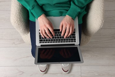 Man working with laptop in armchair, top view