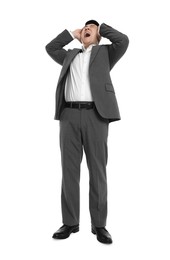 Businessman in suit screaming on white background, low angle view