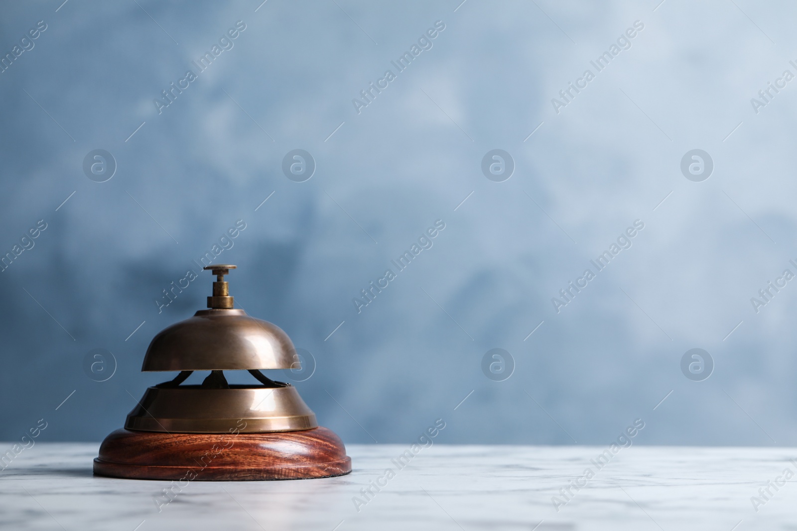 Photo of Hotel service bell on table against blue background. Space for text