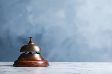 Photo of Hotel service bell on table against blue background. Space for text