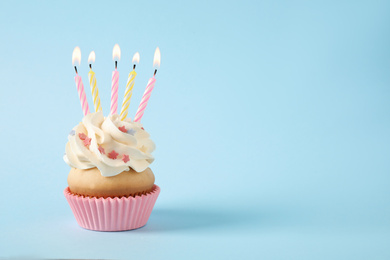 Birthday cupcake with candles on light blue background. Space for text