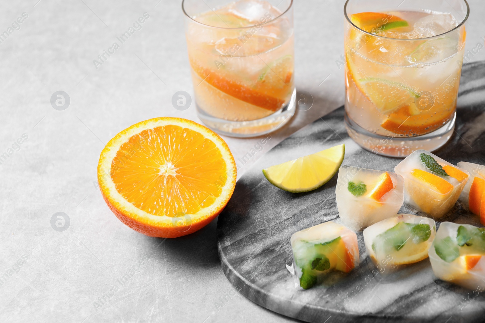 Photo of Ice cubes with orange and mint on light grey table