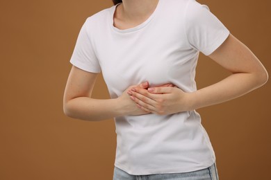 Photo of Woman having heart attack on brown background, closeup