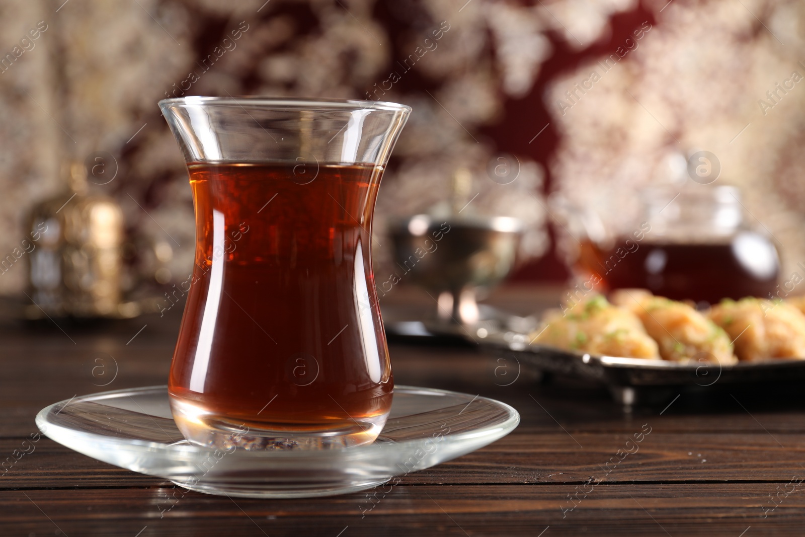 Photo of Traditional Turkish tea in glass on wooden table, closeup. Space for text