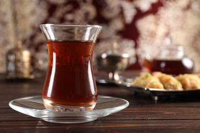 Photo of Traditional Turkish tea in glass on wooden table, closeup. Space for text