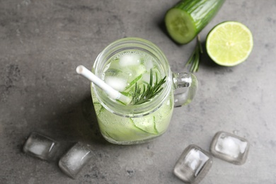 Photo of Mason jar with fresh cucumber water on grey background