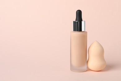 Bottle of skin foundation and sponge on beige background, space for text. Makeup product