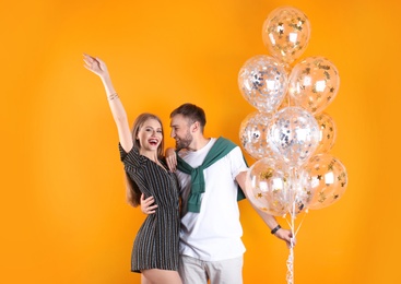 Photo of Young couple with air balloons on color background