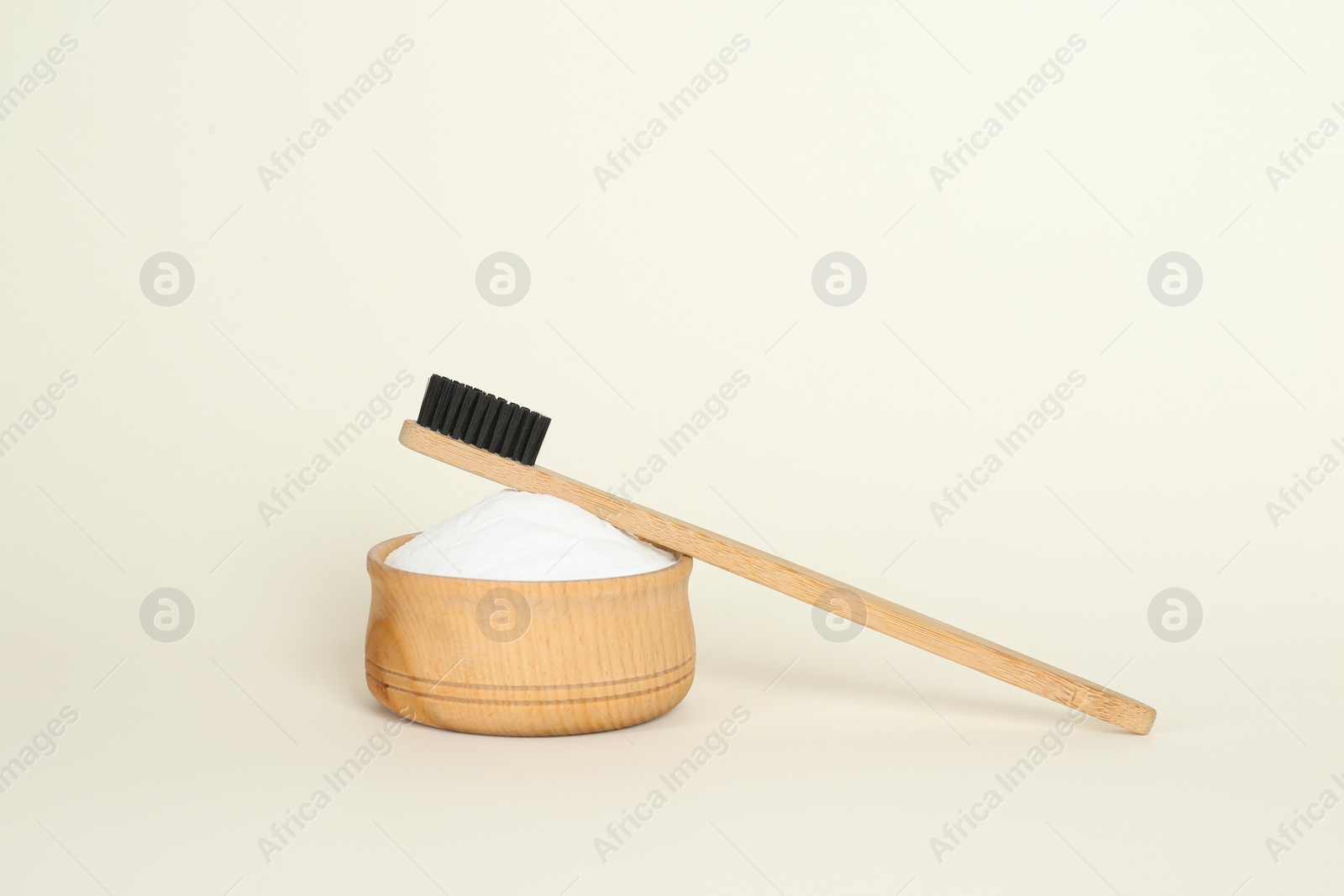 Photo of Bamboo toothbrush and bowl with baking soda on beige background