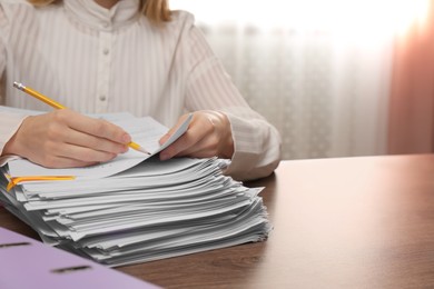 Woman signing documents at wooden table indoors, closeup. Space for text