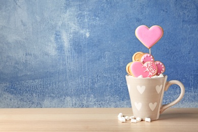 Photo of Decorated heart shaped cookies in cup on table. Space for text