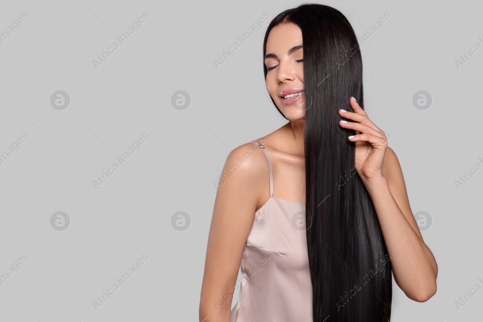 Photo of Portrait of beautiful young woman with healthy strong hair on light grey background, space for text