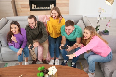 Photo of Group of friends engaged in video game indoors. Celebrating victory