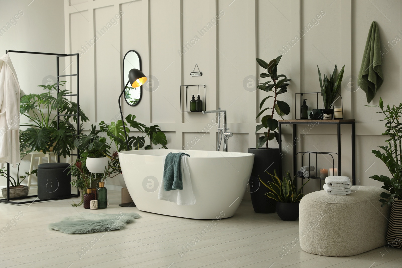 Photo of Stylish bathroom interior with modern tub and beautiful houseplants. Home design