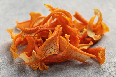 Photo of Dry orange peels on light gray textured table, closeup