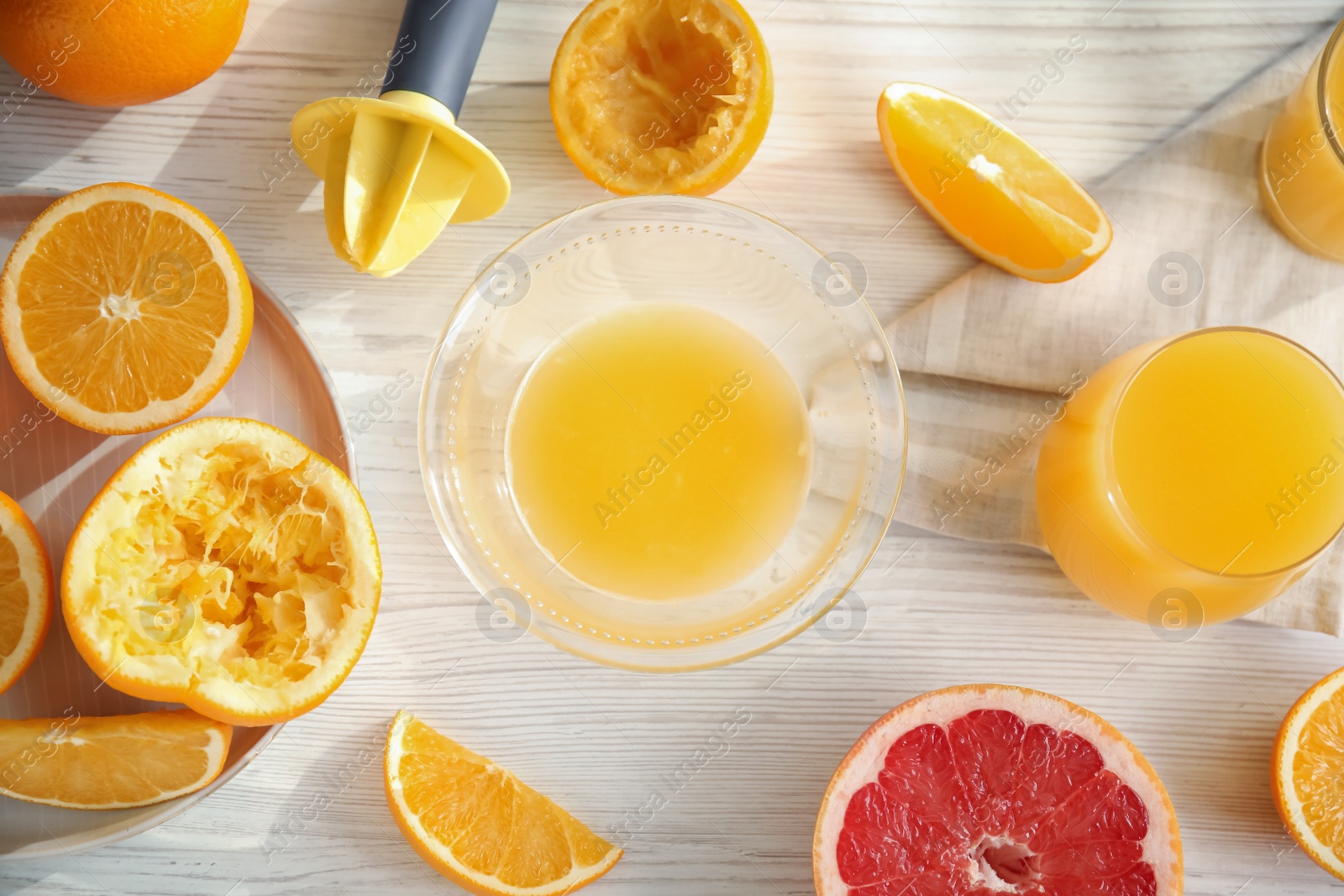 Photo of Freshly made juice, oranges and reamer on wooden table, flat lay