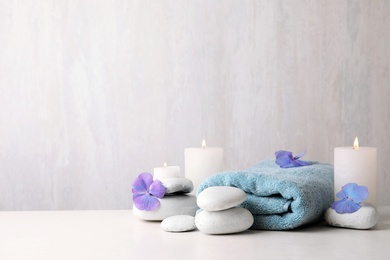 Composition with zen stones, towel and candles on table against light background. Space for text