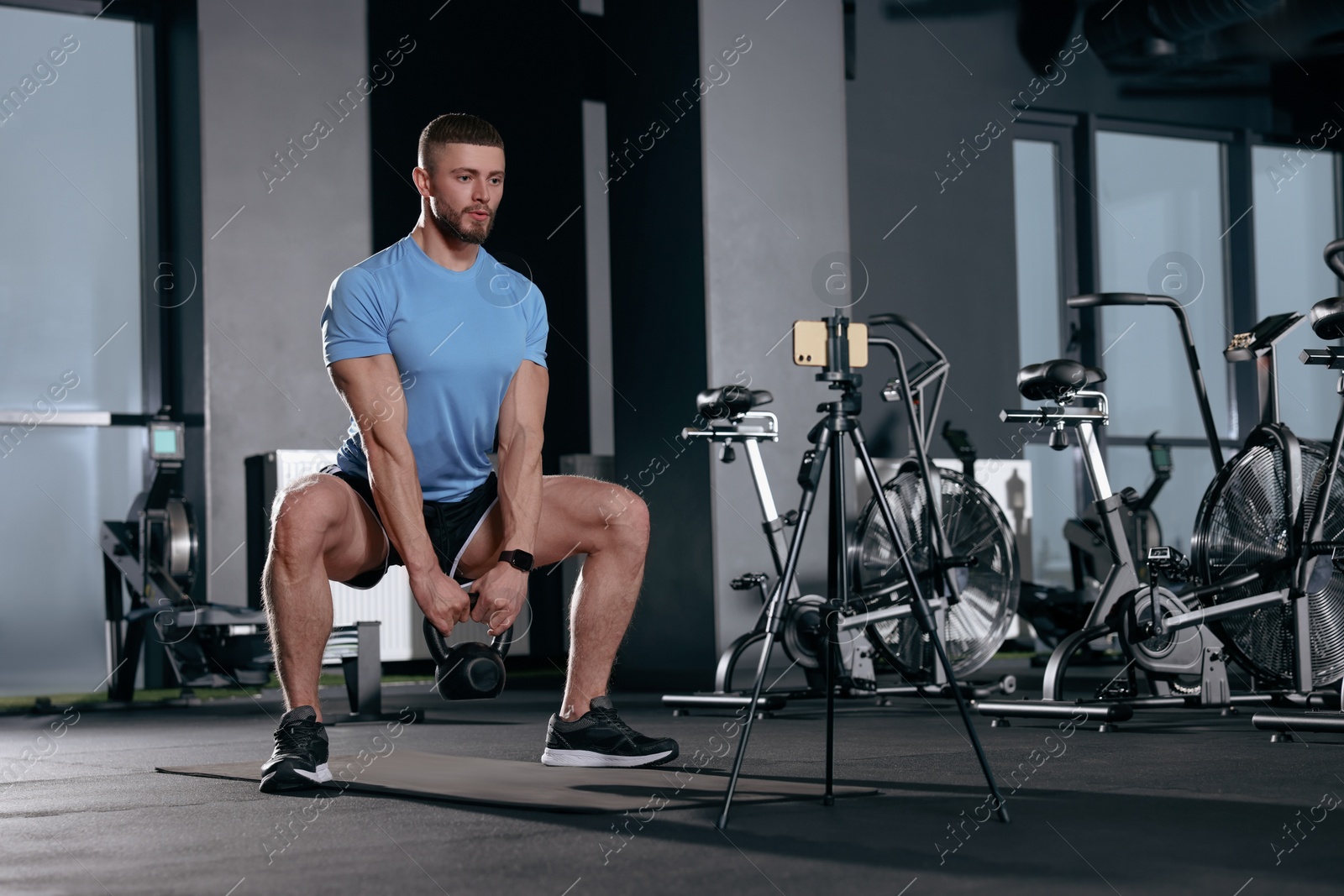 Photo of Trainer streaming online workout with phone at gym