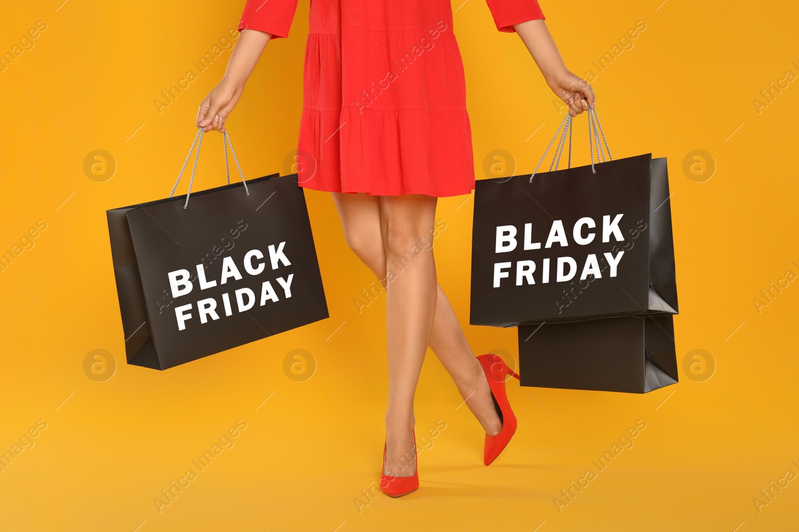 Photo of Woman with shopping bags on yellow background, closeup. Black Friday
