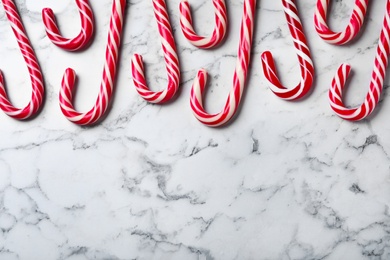 Sweet Christmas candy canes on white marble background, flat lay. Space for text